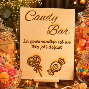 Peut inclure: Un panneau rectangulaire en bois clair sur un petit chevalet avec le texte gravé au laser Candy Bar et La gourmandise est un très joli défaut, accompagné d'illustrations gravées d'une sucette en cœur et d'un bonbon emballé.