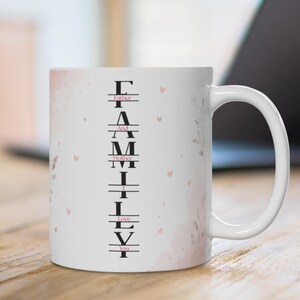 May include: A white ceramic mug featuring a vertical design with the word FAMILY in large black letters. Interspersed between the letters are the words Father, And, Mother, I, Love, You in smaller pink text, accented by soft pink watercolor hearts.