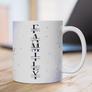 May include: A white ceramic mug featuring a vertical black text design that spells FAMILY, with smaller blue text reading Father And Mother I Love You integrated between the letters. The mug has a light purple watercolor floral and heart pattern.