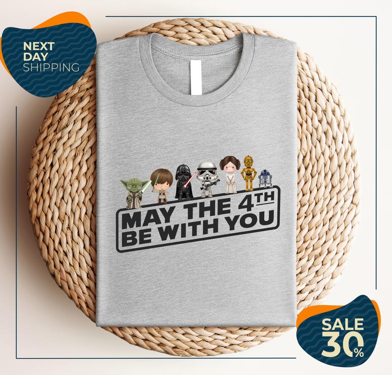 A gray t-shirt with a graphic design featuring characters from the Star Wars franchise, along with the text "May the 4th be with you".