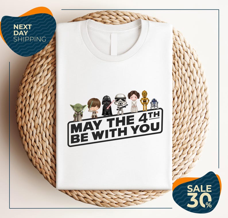 A white t-shirt with a graphic design featuring characters from the Star Wars franchise, along with the text "May the 4th be with you".