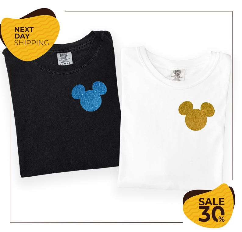 two t-shirts with Mickey Mouse designs, one black and one white, both with glittery Mickey Mouse ears. The t-shirts are folded and placed next to each other, and there are yellow and black sale signs indicating a 30% discount.