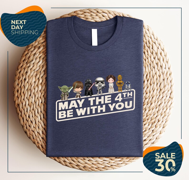 A navy blue t-shirt with a graphic design featuring characters from the Star Wars franchise, along with the text "May the 4th be with you".