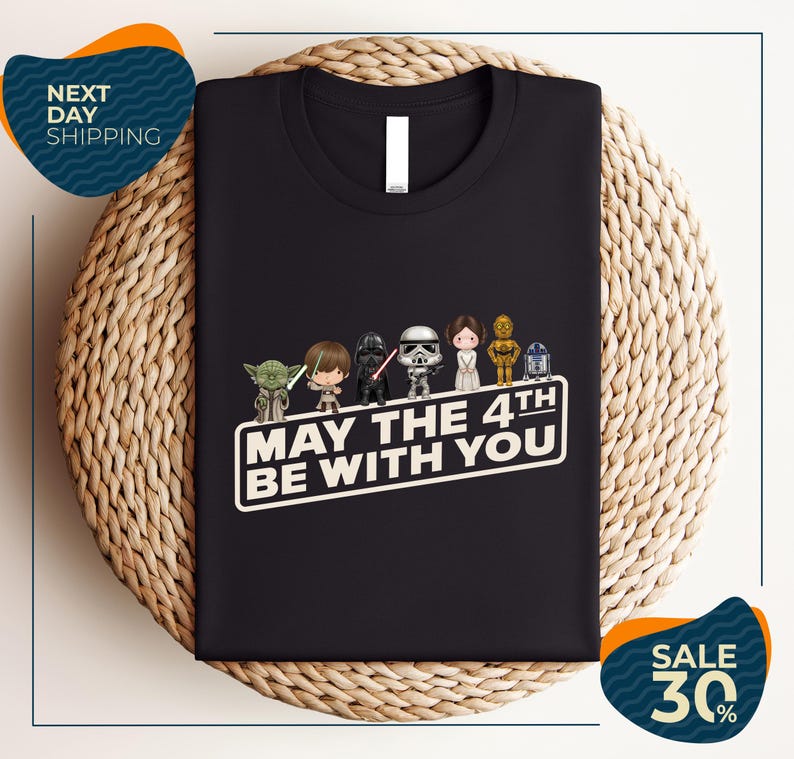 A black t-shirt with a graphic design featuring characters from the Star Wars franchise, along with the text "May the 4th be with you".