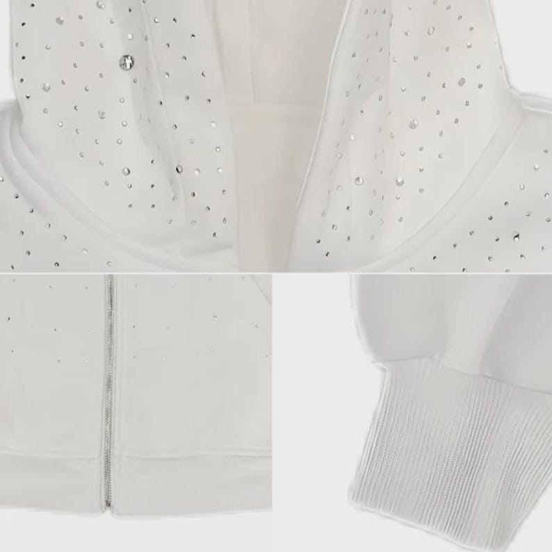 May include: A white hooded sweatshirt with a silver zipper and numerous small, sparkling embellishments. The cuffs and hood lining are ribbed. The overall design is clean and minimalist, with a focus on the decorative elements.