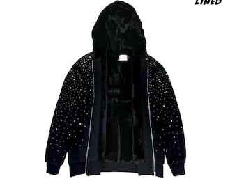 May include: Black zip-up hoodie with a fur-lined interior and hood. The black jacket is embellished with white star-like accents. The text "500 GSM" and "FUR LINED" are visible on the image.