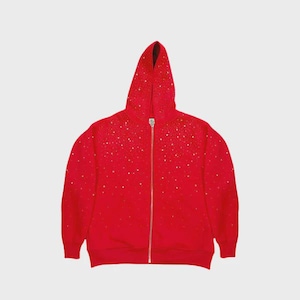 May include: A red hooded zip-up sweatshirt with a scattering of gold-colored embellishments. The sweatshirt has a full-length zipper and a hood. The fabric appears to be a soft material. The background is a solid, light gray color.