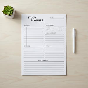 May include: A white study planner with the words "STUDY PLANNER" printed at the top. The planner includes sections for a time table, study hours, deadlines, goals, and notes. A white pen rests on the right side of the planner.