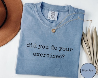 May include: A blue jean colored short-sleeve t-shirt with a crew neckline and a Comfort Colors brand label at the inner collar. The shirt features the black text "did you do your exercises?" printed in a typewriter-style font across the chest.