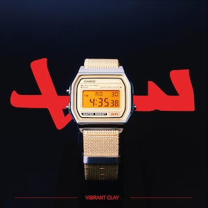 Peut inclure: Une montre numérique Casio avec un cadran doré et un bracelet en tissu beige. L'heure affichée est 16h35m38 le lundi. La montre est résistante à l'eau. Le texte "VIBRANT CLAY" est en bas.