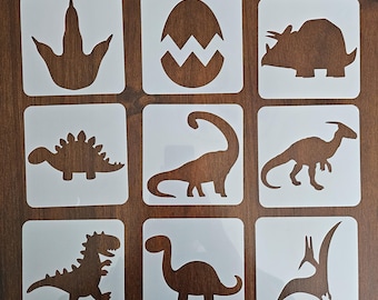 May include: Nine white square stencils with brown dinosaur designs. The stencils feature a dinosaur footprint, a cracked egg, a Triceratops, a Stegosaurus, a Brontosaurus, a Parasaurolophus, a Tyrannosaurus Rex, a small dinosaur, and a Pterodactyl.