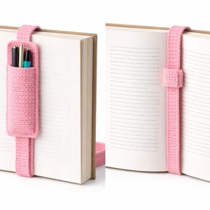 Peut inclure: Marque-page rose en crochet avec un porte-stylo attaché à un livre. Le marque-page est fait d'un fil doux et texturé et comporte une boucle qui s'adapte au sommet du livre. Le porte-stylo est une petite pochette pouvant contenir plusieurs stylos ou crayons.