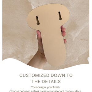 May include: A light beige, mushroom-shaped object with a smooth, flat backing featuring two vertical keyhole slots for mounting. The text below reads: CUSTOMIZED DOWN TO THE DETAILS. Your design, your finish. Choose between a sleek glossy or an elegant matte surface. We will also gladly add custom hook holes to the smooth backing, tailored exactly to your needs.