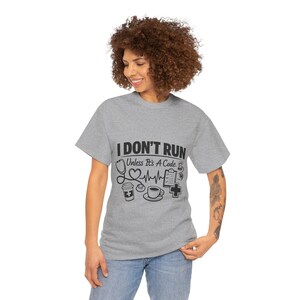 May include: A gray t-shirt with the text "I DON'T RUN Unless It's A Code" and medical-themed graphics. The design includes a stethoscope, heart rate, coffee cup, and medical cross.