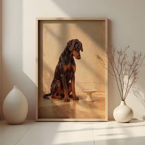 May include: A framed wall art print featuring a black and tan Doberman dog sitting on a floor next to a small pedestal bowl. The dog is positioned in the center of the composition, facing slightly downward toward the bowl in a warm-toned room.