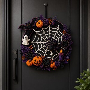 K&ouml;nnte beinhalten: Ein runder Halloween-Kranz aus H&auml;kelarbeit mit einem wei&szlig;en Spinnennetz in der Mitte, einer schwarzen Spinne, einem wei&szlig;en Geist, orangefarbenen K&uuml;rbissen, violetten Blumen und einer schwarzen Fledermaus. Er ist mit einer kleinen lila Kerze verziert.