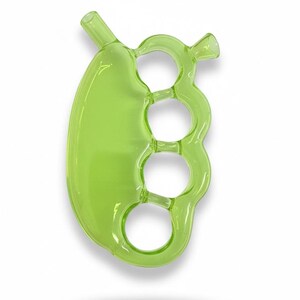 May include: A transparent, lime green glass pipe with a unique design. The pipe features a rounded, oblong bowl connected to a series of three finger-sized rings, and a mouthpiece. The overall shape resembles a set of brass knuckles.
