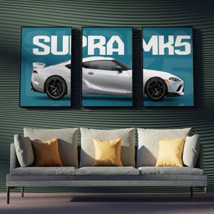 May include: A three-panel wall art set featuring a white sports car on a teal background. The text SUPRA MK5 is displayed in large white block letters across the top of the three frames, showing the rear, side, and front profile of the vehicle.