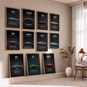 Puede incluir: Una colección de once pósteres verticales enmarcados en una pared, cada uno con una ilustración de un coche deportivo diferente sobre fondo negro con texto blanco que identifica el modelo, la marca y el año, en marcos de madera clara.