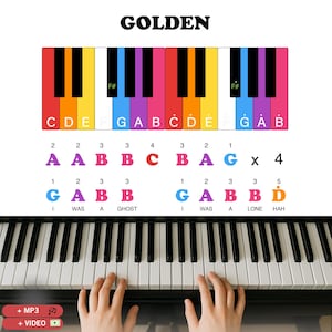 Op de afbeelding: Een pianotoetsenbord met kleurrijke noten, gelabeld met letters en cijfers. Het woord "GOLDEN" staat bovenaan. De handen van een persoon spelen piano. De afbeelding bevat de tekst "+ MP3" en "+ VIDEO".