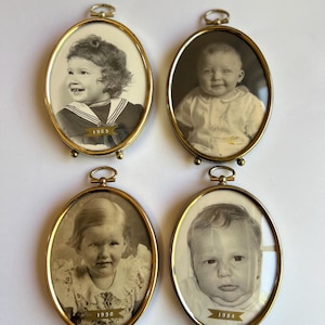 May include: Four vintage oval picture frames with gold-colored metal frames. Each frame holds a black and white photograph of a child. The frames are labeled with the years 1963, 1936, and 1984. The frames have a small loop at the top for hanging.