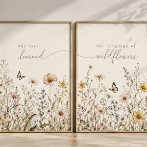 May include: Two framed art prints with floral and butterfly illustrations. The left print reads "our love learned" and the right print reads "the language of wildflowers". The artwork features a beige background with colorful wildflowers.
