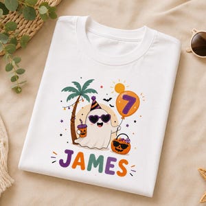 May include: A white t-shirt featuring a graphic of a ghost wearing heart-shaped sunglasses and a party hat, standing next to a palm tree. The ghost holds an orange balloon with the number 7 and a jack-o'-lantern bucket. The name JAMES is printed below.