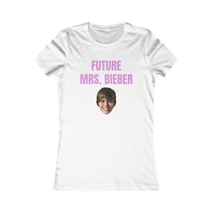 May include: White t-shirt with the text "FUTURE MRS. BIEBER" in pink letters and a photo of a smiling person. The shirt has a crew neck and short sleeves.