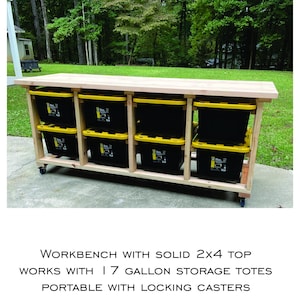 May include: A wooden workbench with a solid 2x4 top, designed to accommodate 17-gallon storage totes. The workbench is constructed with a light-colored wood frame and features locking casters for portability. The workbench is shown outdoors.