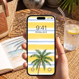 Pu&ograve; includere: Uno smartphone mostra uno sfondo tropicale con strisce gialle e blu e una palma. L'ora &egrave; 9:41, luned&igrave; 6 gennaio. Il telefono &egrave; tenuto in mano. &Egrave; visibile un bicchiere d'acqua con una fetta di limone.