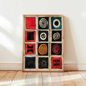 Puede incluir: Una obra de arte enmarcada con una cuadrícula de doce paneles cuadrados. Cada panel muestra un diseño abstracto único en colores llamativos como rojo, negro, azul y amarillo. Los diseños incluyen espirales, círculos y formas geométricas. El marco es de madera clara.