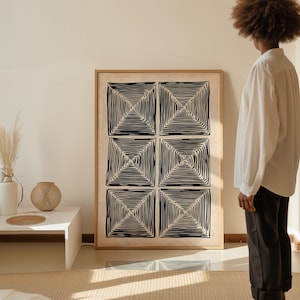 May include: Large framed artwork featuring six black and white square designs. Each square has a concentric pattern of lines, creating a visual depth. The artwork is in a light-colored wooden frame, adding a touch of warmth to the piece.