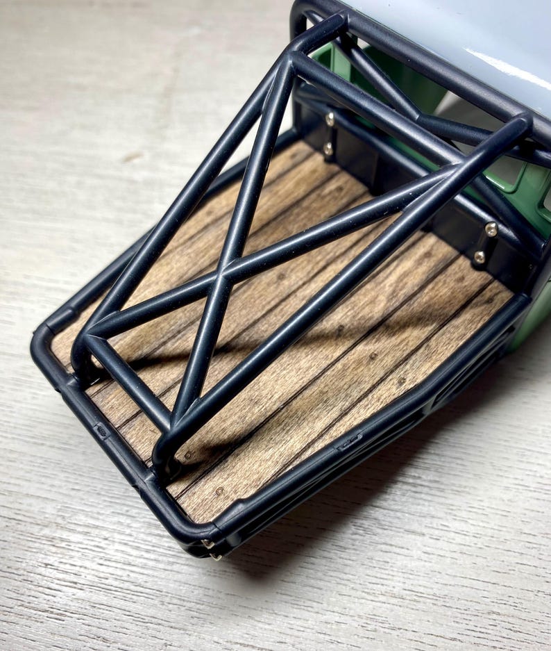 Peut inclure: Gros plan sur une maquette de benne de camion. La benne est compos&eacute;e de planches de bois et d'une cage de protection en m&eacute;tal noir. La benne est verte et grise.