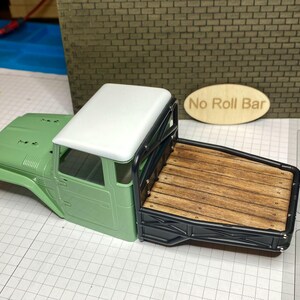 Peut inclure: Maquette d'un pick-up vert avec un toit blanc et une benne en bois. La benne est encadr&eacute;e de m&eacute;tal noir. Les mots "No Roll Bar" sont sur un panneau ovale en bois.