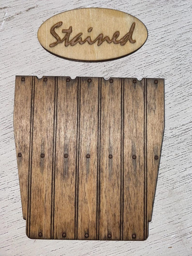 Peut inclure: Panneau en bois avec le mot "Stained" en &eacute;criture cursive au-dessus d'une pi&egrave;ce en forme de tonneau en bois. La pi&egrave;ce en forme de tonneau comporte des lignes verticales et de petits points fonc&eacute;s. Le bois a une teinte brune chaude.