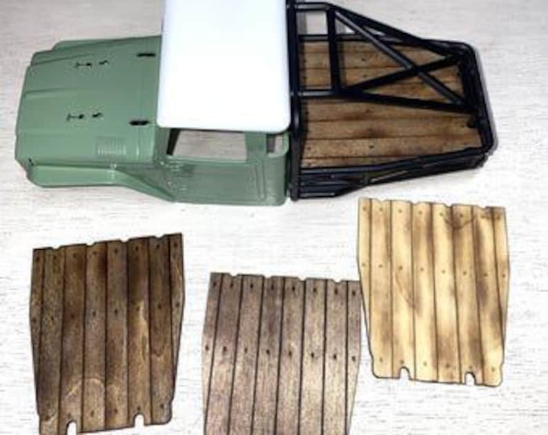 Peut inclure: Une cabine de camion mod&egrave;le vert clair et blanc avec un cadre en m&eacute;tal noir et un plateau en bois. Trois panneaux en bois de diff&eacute;rentes nuances de marron sont affich&eacute;s en dessous.