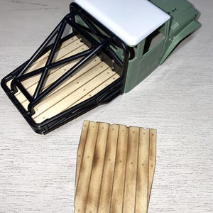 Peut inclure: Une carrosserie de camion mod&egrave;le avec un toit blanc, une cabine verte et une cage de protection noire. La benne du camion pr&eacute;sente un design en planches de bois. Une pi&egrave;ce de planche de bois s&eacute;par&eacute;e est &eacute;galement visible.