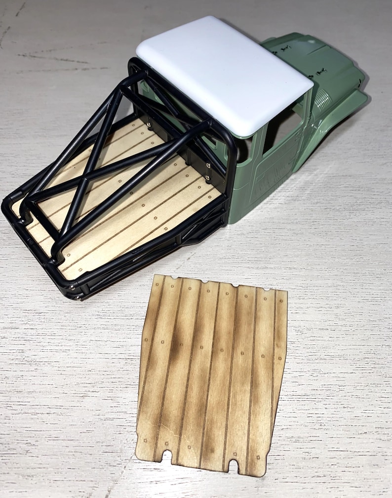 Peut inclure: Une carrosserie de camion mod&egrave;le avec un toit blanc, une cabine verte et une cage de protection noire. La benne du camion pr&eacute;sente un design en planches de bois. Une pi&egrave;ce de planche de bois s&eacute;par&eacute;e est &eacute;galement visible.