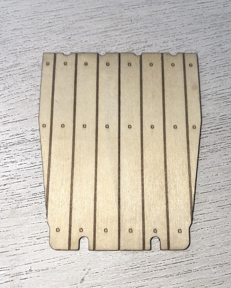 Peut inclure: Panneau en bois d&eacute;coup&eacute; au laser, compos&eacute; de planches verticales. Le panneau est de couleur brun clair et pr&eacute;sente de petits trous espac&eacute;s r&eacute;guli&egrave;rement en haut et au milieu de chaque planche. Le bas a deux d&eacute;coupes courbes.