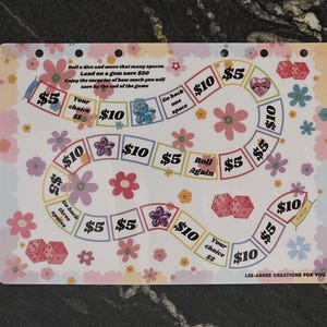 May include: A rectangular game board featuring a winding path with squares labelled with dollar amounts like $5 and $10, dice illustrations, and floral patterns. Text includes: Roll a dice and move that many spaces. Land on a gem save $20.