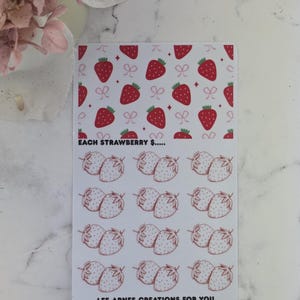 May include: A sheet of stickers with a strawberry design. The top half has red strawberries and pink bows on a white background. The bottom half features pairs of strawberries. Text on the sticker reads "EACH STRAWBERRY $....." and "LEE-ARNES CREATIONS FOR YOU."