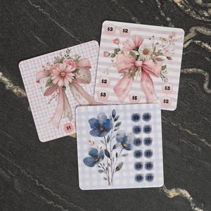 May include: Three square sticker sheets featuring floral designs. One sheet has a pink bow and flowers on a plaid background with a $1 label. Another has a pink bow and flowers on stripes with $2, $3, and $5 labels. The third has blue flowers and $1, $2, $3, $5 labels.