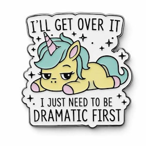May include: A yellow unicorn badge with a light blue mane and tail, and a pink and white horn. The badge has the text "I'll get over it. I just need to be dramatic first" in black letters on a white background.