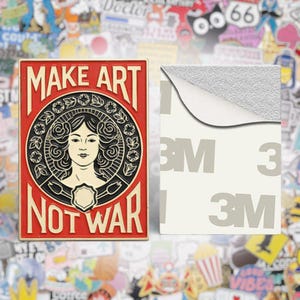 Può includere: Un adesivo rettangolare rosso e nero con le parole "MAKE ART NOT WAR" attorno al volto di una donna. L'adesivo è accanto a un supporto adesivo bianco con il logo "3M".