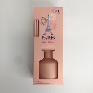 May include: A pink rectangular box for an Air by Air Paris White Flowers reed diffuser. The packaging features a graphic of the Eiffel Tower, fireworks, and a glass bottle. It includes 7 sticks, 7.8 inches long, and 3.04 fluid ounces of solution.