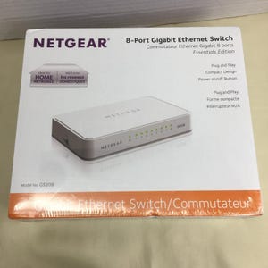 以下が含まれることがあります： Netgear 8ポートギガビットイーサネットスイッチ（モデルGS208）の白い箱。コンパクトなデザイン、プラグアンドプレイ機能、電源オン/オフボタンが特徴です。パッケージには英語とフランス語で製品名とテキストが記載されています。