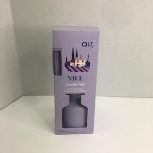 May include: A light purple rectangular cardboard box for an air reed diffuser. The front features the text "air.", "NICE", "Lavender Fields", and "REED DIFFUSER WITH GLASS BOTTLE". An illustration shows a house in a lavender field.