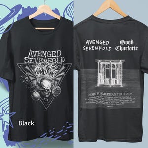 Peut inclure: T-shirt noir avec le nom du groupe "Avenged Sevenfold" en blanc, et un motif de crâne avec des ailes. Le dos du t-shirt affiche "Avenged Sevenfold" et "Good Charlotte", une image de gazebo et le texte "North American Tour 2026".