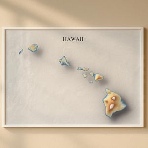 May include: A framed print of the Hawaiian Islands. The map features a 3D-style rendering of the islands with beige, blue, and brown tones. The word "HAWAII" is printed in black at the top of the frame.