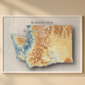 Puede incluir: Mapa enmarcado del estado de Washington, con un diseño topográfico en 3D. El mapa utiliza azules, marrones y bronceados, y el nombre del estado está impreso en la parte superior. La obra de arte está en un marco blanco. Medidas en centímetros.